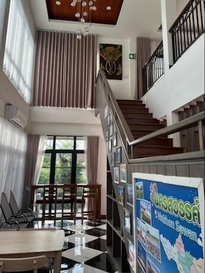 Vestíbulo de hotel con una escalera, un comedor y una recepción.