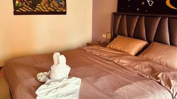 A neatly made bed with a brown cover, a white towel, and a white robe on it.