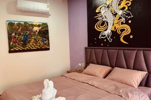 Un dormitorio con cama, cabecera, aire acondicionado de pared y un cuadro.