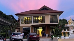 Una casa a due piani con tetto rosso, ampie finestre e un portico.