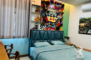 Un dormitorio con una cama, un escritorio y un mural colorido en la pared.