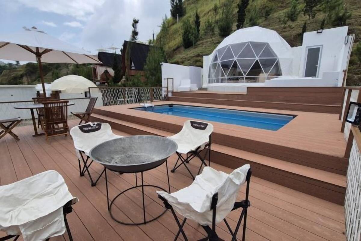 Ein Poolbereich mit Whirlpool, Liegestühlen und Sonnenschirmen.