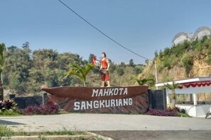 Een persoon staat op een podium met een spandoek waarop 'MAHKOTA SANGKURIANG' staat.