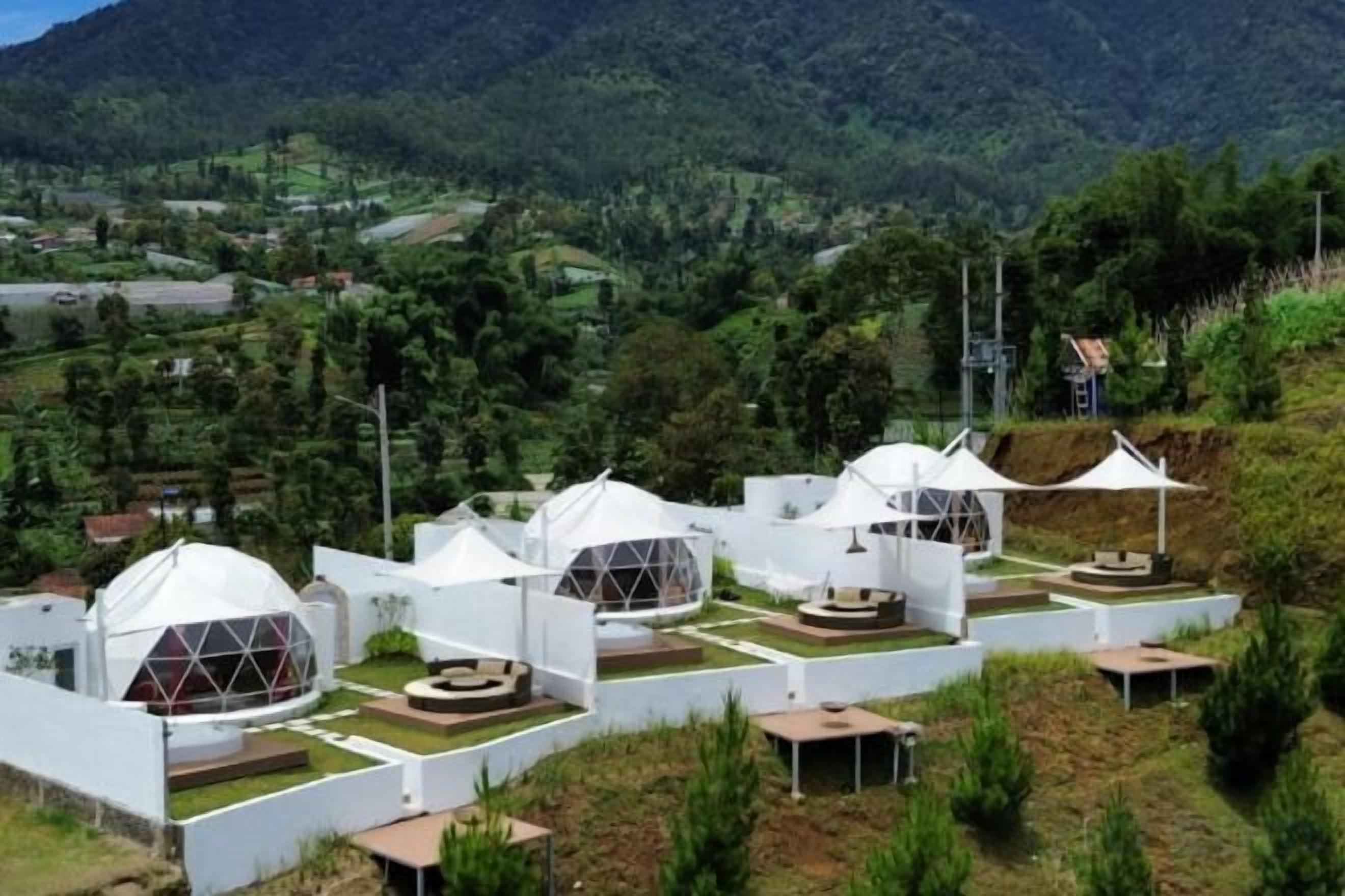 A series of dome-shaped structures with flat roofs, arranged in a row on a hillside with a view of a mountainous landscape.