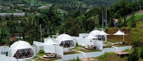 A series of dome-shaped structures with flat roofs, arranged in a row on a hillside with a view of a mountainous landscape.