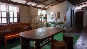 A room with a wooden bench, a table, and a green carpet. - Baanpai Hostel (Pai)