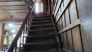 A wooden staircase with a handrail, leading to an upper level. - Baanpai Hostel (Pai)