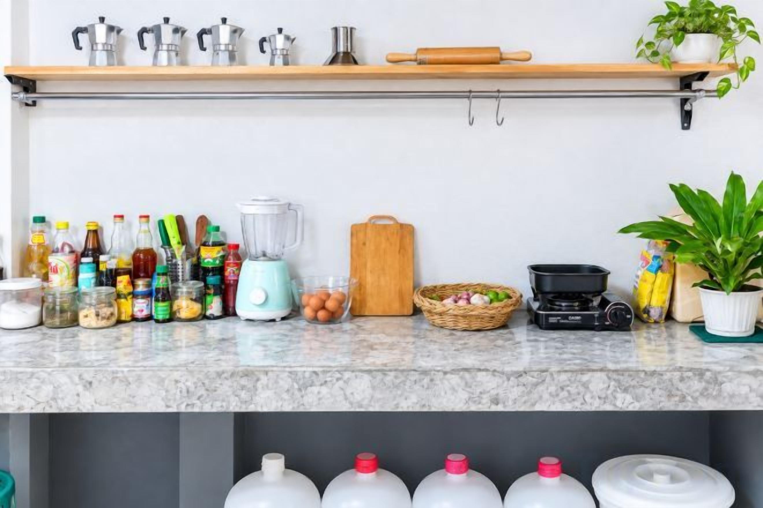 A kitchen counter with various cooking utensils, bottles, and appliances.
