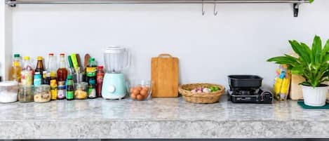 Un piano di lavoro in cucina con diversi utensili da cucina, bottiglie ed elettrodomestici.