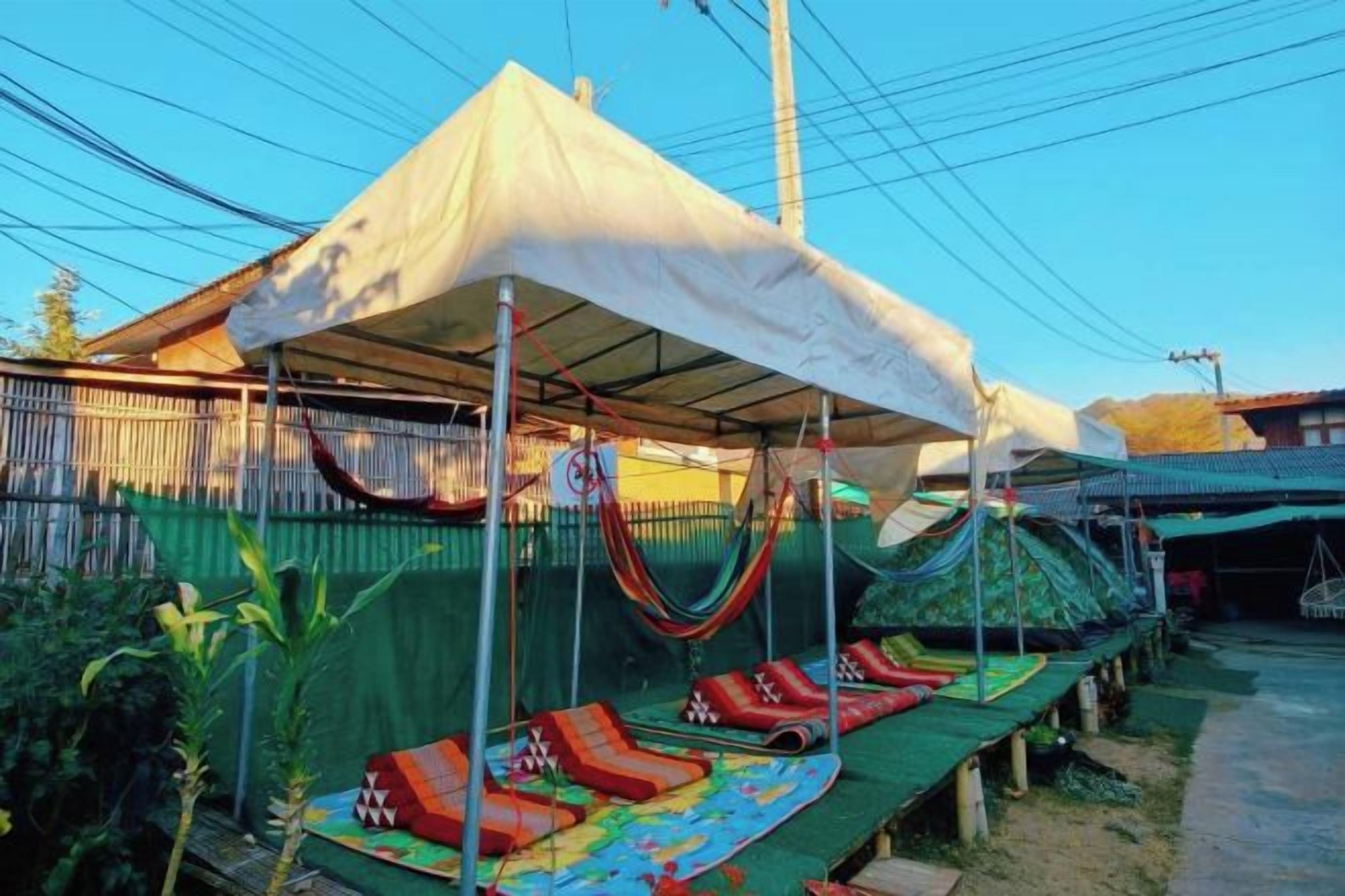 A covered outdoor area with a hammock and lounge chairs.