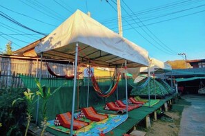 A covered outdoor area with a hammock and lounge chairs. - Baanpai Hostel (Pai)