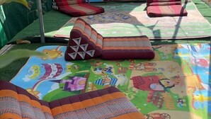 A room with a colorful, patterned carpet and several cushions. - Baanpai Hostel (Pai)