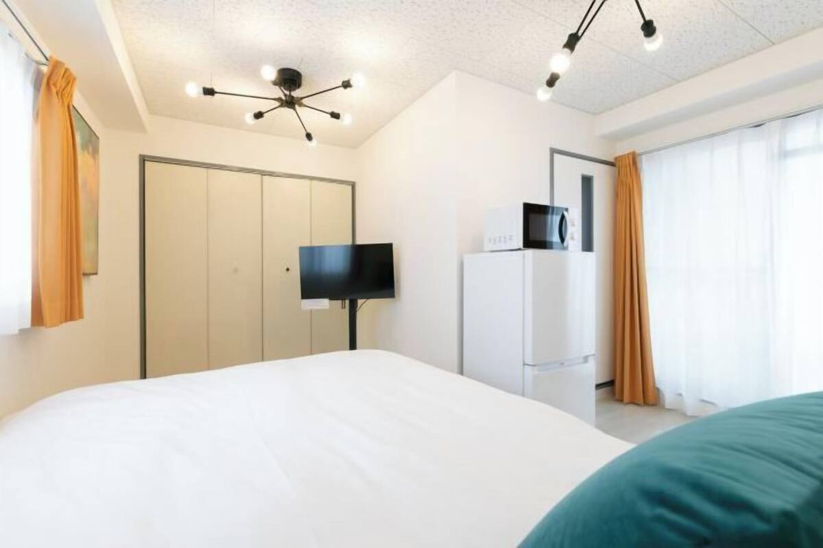 Ein Hotelzimmer mit Bett, Fernseher, Kühlschrank und Kleiderschrank.