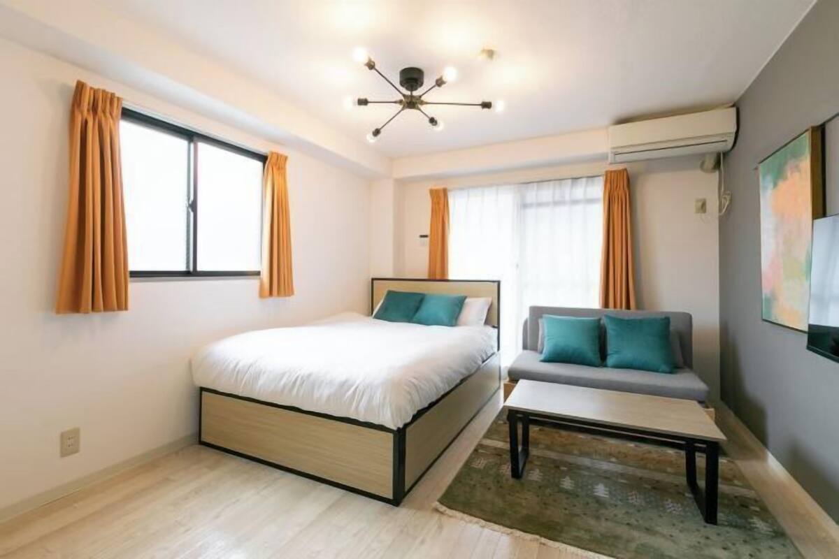 A modern bedroom with a bed, a sofa, a coffee table, and a ceiling light fixture.