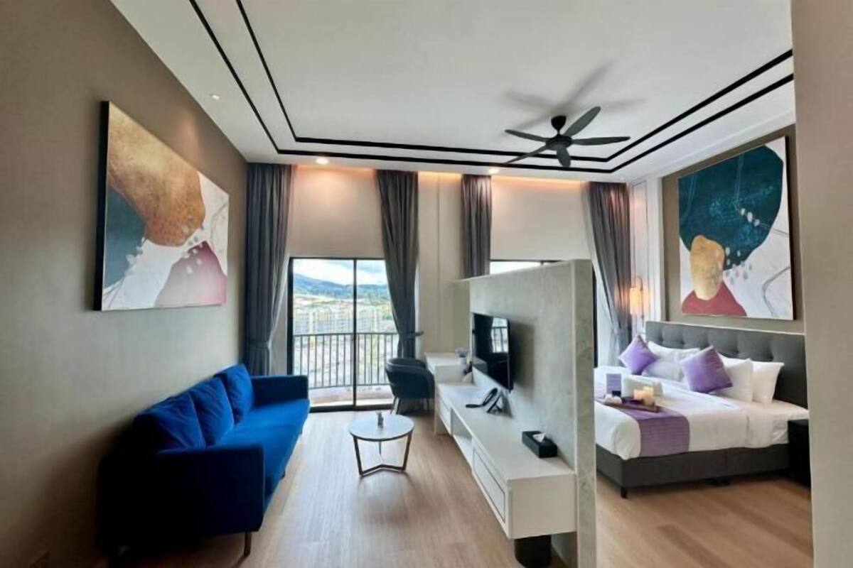 A modern hotel room with a sofa, a bed, a TV, and a balcony with a view.