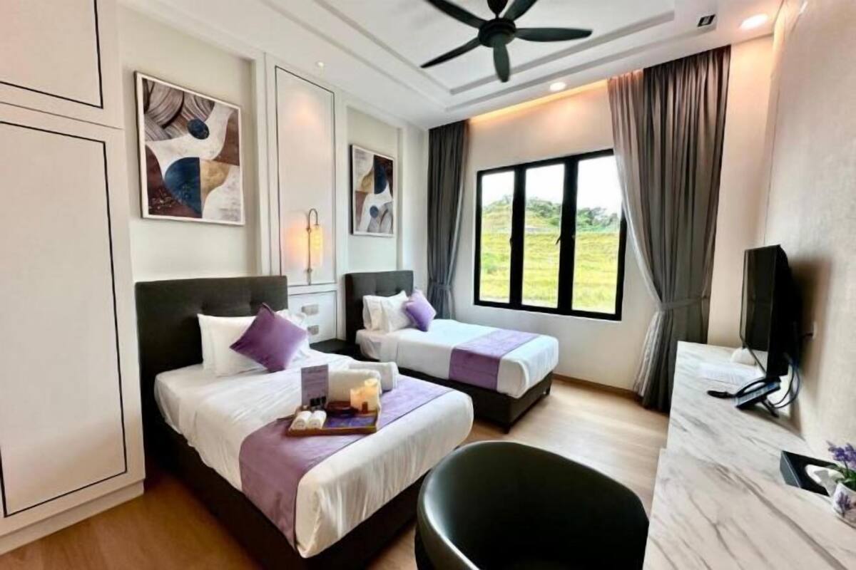 A hotel room with two beds, a desk, a chair, a ceiling fan, and artwork on the walls.