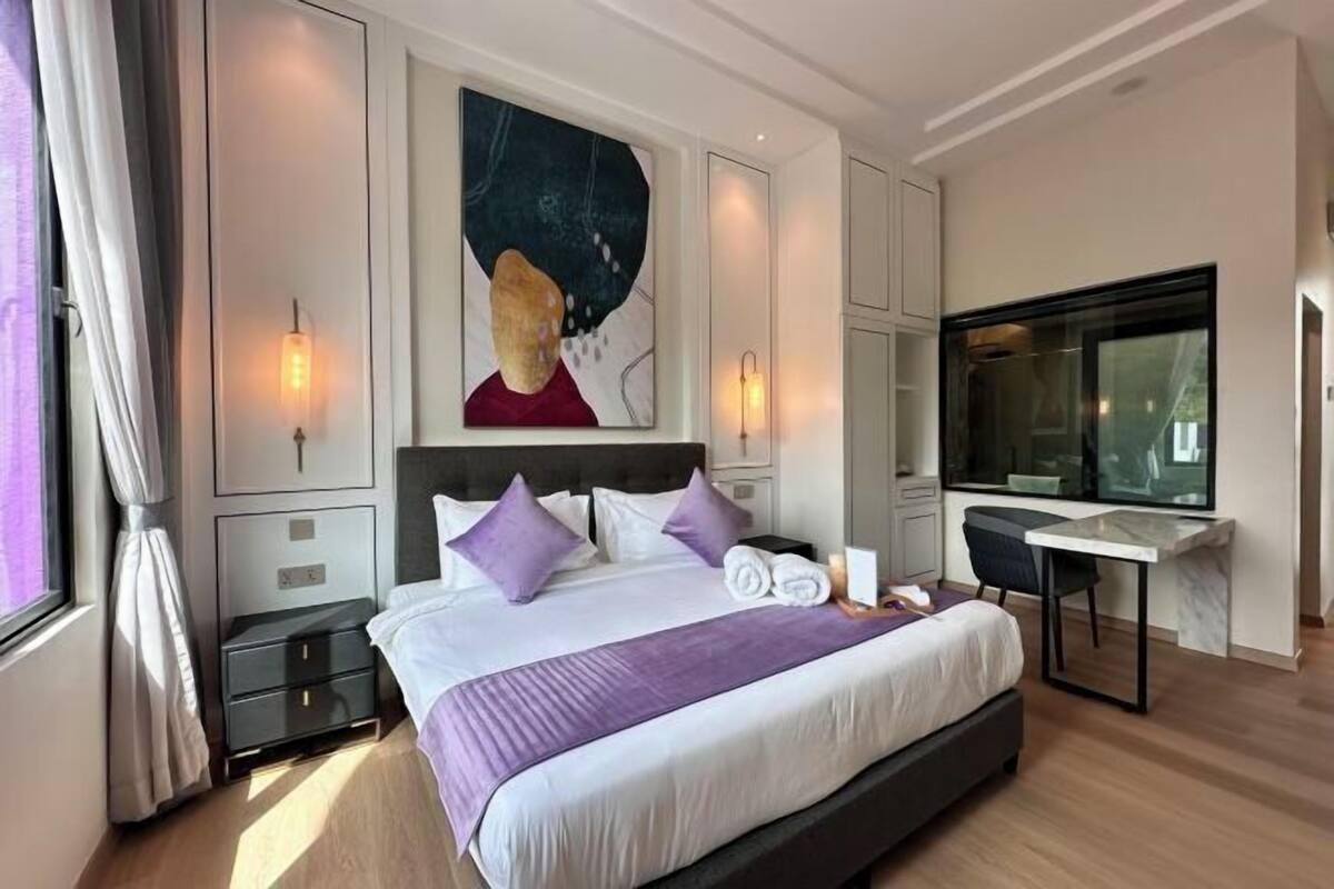A modern hotel room with a large bed, a desk, and a large window.