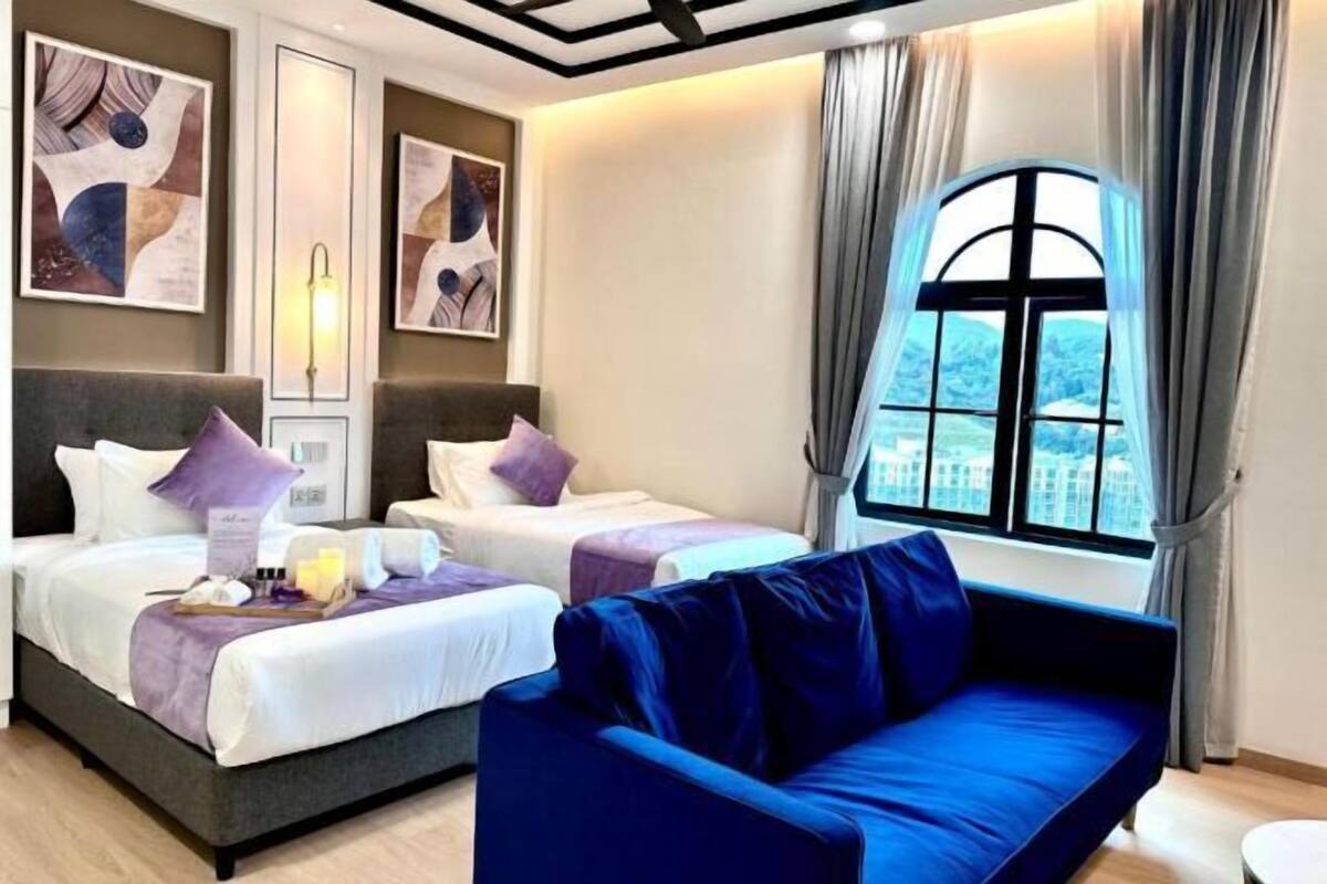 A hotel room with two beds, a blue sofa, and a large window with a view.