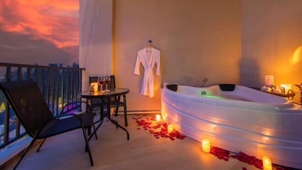 A balcony with a table and chairs, a white bathtub, and a robe hanging on the wall. - Cameron Lavender Mansion (Brinchang)