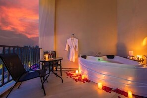 A balcony with a table and chairs, a white bathtub, and a robe hanging on the wall. - Cameron Lavender Mansion (Brinchang)