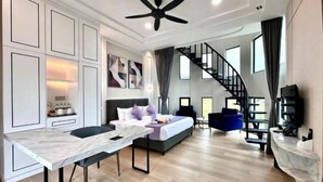 A modern hotel room with a bed, a desk, a chair, a staircase, and a ceiling fan. - Cameron Lavender Mansion (Brinchang)
