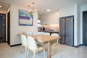 A modern kitchen with white cabinets, a central island, and a dining area with a wooden table and chairs.