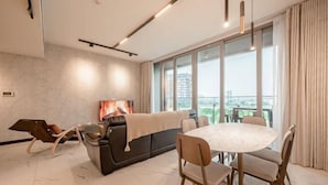 A modern living room with a sofa, a round dining table, and chairs. - The Metropole Riverside Apartment (Ho Chi Minh City)