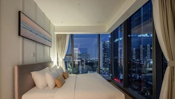 A modern bedroom with a large bed, a city view through floor-to-ceiling windows, and a minimalist decor. - The Metropole Riverside Apartment (Ho Chi Minh City)