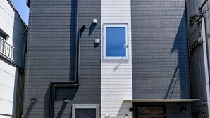 Ein Gebäude mit grauer Fassade, einem kleinen Fenster und einer Tür.