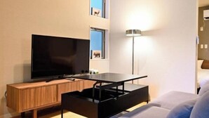 Ein modernes Wohnzimmer mit Flachbildfernseher, Holzschrank und Stehlampe.