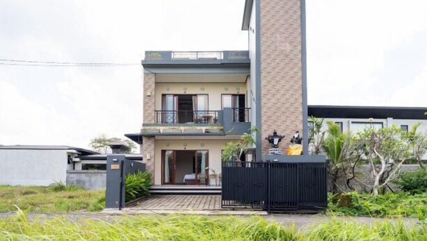 Una casa moderna de dos pisos con balcón, entrada protegida por reja y un pequeño jardín.