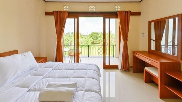 A bedroom with a bed, a desk, a chair, and a balcony with curtains.