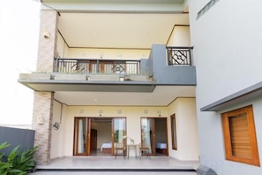 Un edificio de dos pisos con un balcón, un comedor y una escalera que sube al nivel superior.