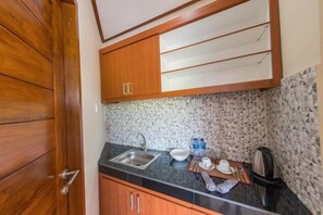 Cocina compacta con lavamanos, encimera y armarios de madera.