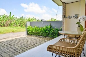 A balcony with a tiled floor, a wicker chair, a small table, and a potted orchid. - MangBo House by The Lavana (Bali)