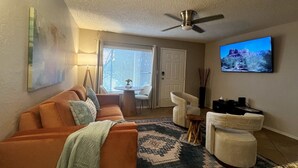 A living room with a sofa, armchairs, a coffee table, and a television mounted on the wall. - Relaxing Sedona Condo | Walk to Dining • Bell Rock (Sedona)