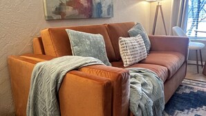 A living room with a brown sofa, a patterned rug, a floor lamp, and a painting on the wall. - Relaxing Sedona Condo | Walk to Dining • Bell Rock (Sedona)