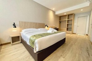 Une chambre d’hôtel comprenant un lit, des lampes de chevet, une armoire et une étagère intégrée.