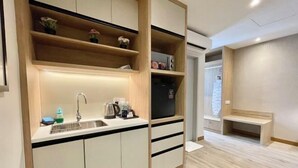 A modern kitchen with a built-in sink, wooden shelves, and a bench in the adjacent area. - LV Modern Suite Langkawi by Zervin (Langkawi)