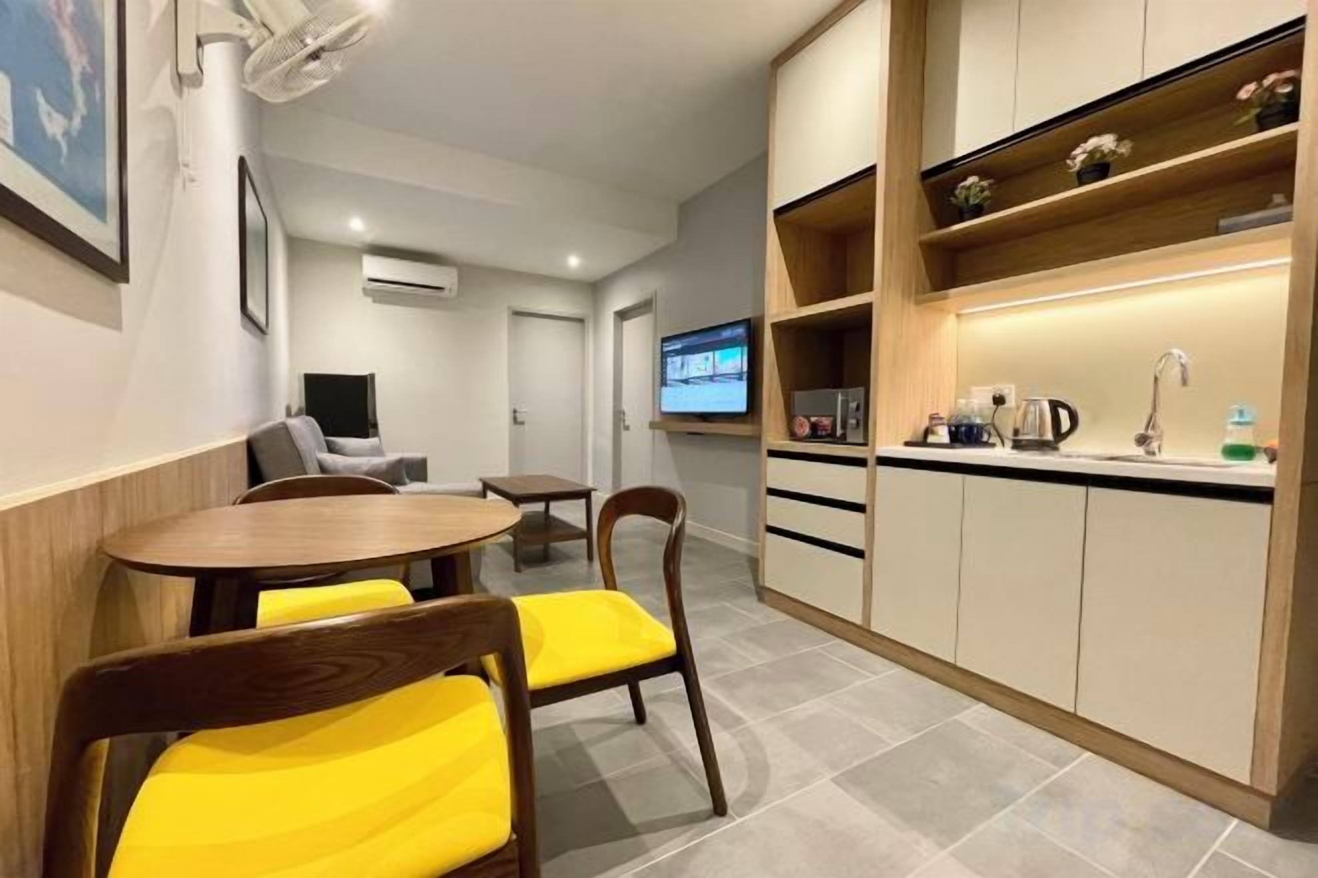 A compact hotel room with a dining area, a kitchenette, and a television.