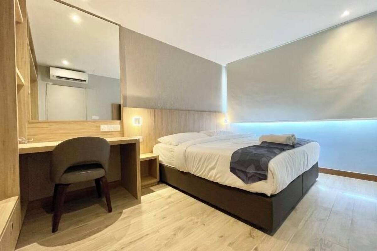 Een moderne hotelkamer met een bed, bureau, stoel en een grote spiegel.