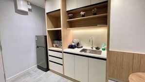 A compact kitchen with built-in cabinets, a refrigerator, and a sink. - LV Modern Suite Langkawi by Zervin (Langkawi)