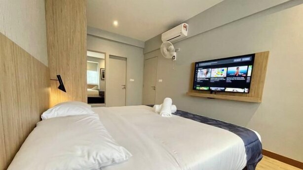 A hotel room with a bed, a TV mounted on the wall, and a door leading to another room. - LV Modern Suite Langkawi by Zervin (Langkawi)