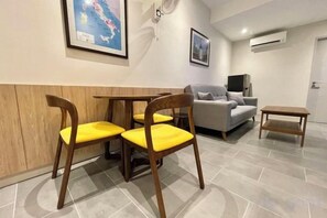 A room with a wooden table and chairs, a grey sofa, and a small table.
