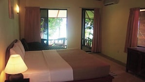 Quarto de hotel com cama, mesa de cabeceira com abajur, escrivaninha e vista para o exterior.