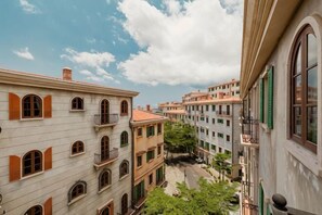 A narrow street with buildings on either side, balconies, and a clear sky. - Little Sun Homestay - Free Buggy Tour Check-in Sunset Town (Phu Quoc Island)