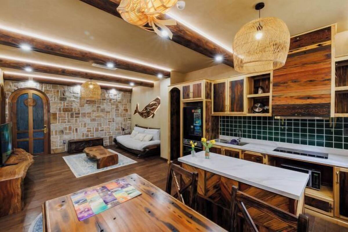 A rustic interior with a stone fireplace, wooden cabinets, and a dining area.