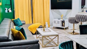 Una sala de estar moderna con sofá, mesa de centro, televisor y elementos decorativos.