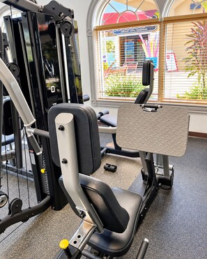 Et fitnessrum med træningsudstyr, et vindue med persienner og udsigt ud