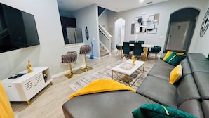 Una sala de estar moderna con un sofá, una mesa de centro, un televisor y una escalera que lleva a otra habitación.